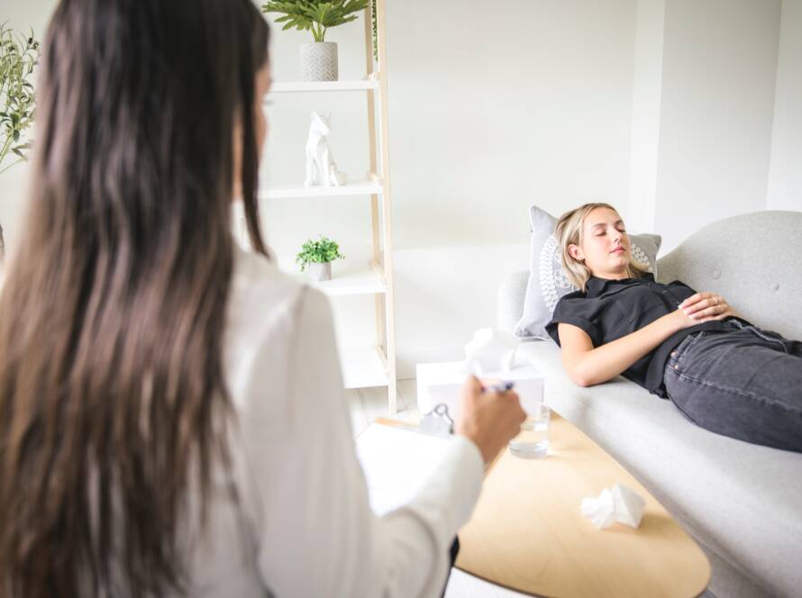 Frau liegt auf Liege bei Hypnosetherapeutin